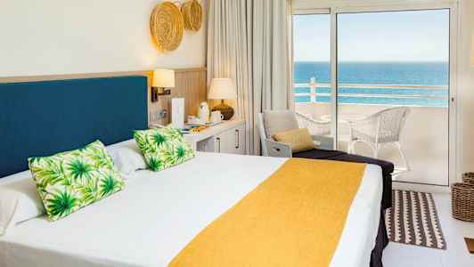 Hotelværelse med dobbeltseng og havudsigt fra altan. (AI-genereret tekst)