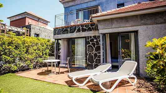 Billede af en terrasse med liggestole og siddepladser ved et hus. (AI-genereret tekst)