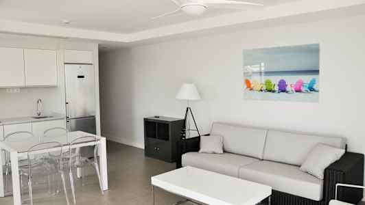 Moderne indrettet stue med sofa, sofabord, spisebord og køkken. (AI-genereret tekst)