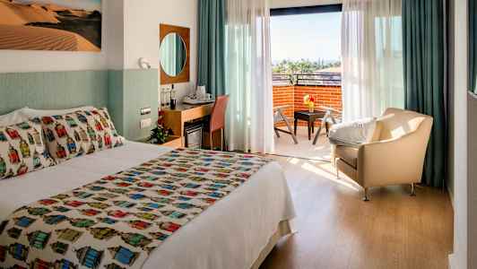 Hotelværelse med dobbeltseng, siddeområde og en altan med udsigt. (AI-genereret tekst)