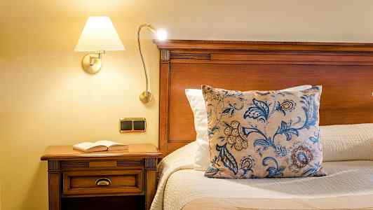 Seng med træstruktur, pyntepude og bog på natbordet. (AI-genereret tekst)