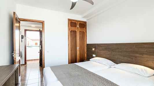 Dobbeltværelse med to senge, dør til altan og garderobe. (AI-genereret tekst)