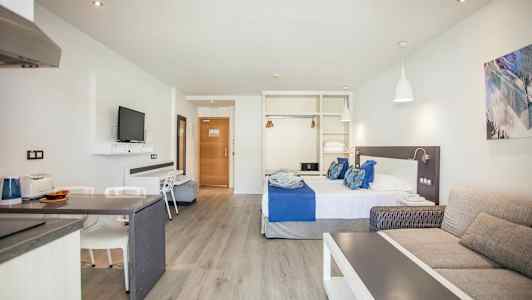 Hotelværelse med seng, sofa og TV. (AI-genereret tekst)