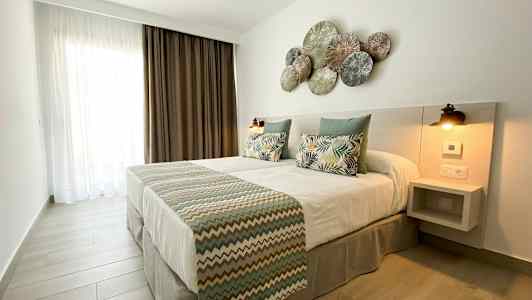 Et soveværelse med en dobbeltseng, pyntepuder og et dekoreret hovedgærde. (AI-genereret tekst)