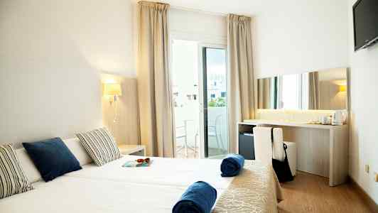 Hotelværelse med to enkeltsenge, balkon og skrivebord. (AI-genereret tekst)