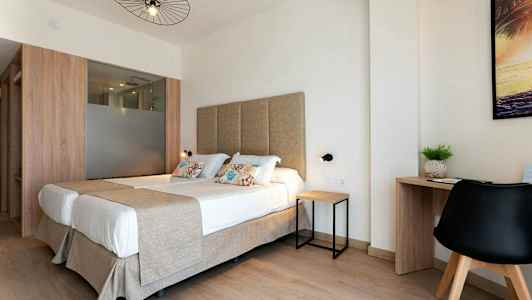 Et lyst hotelværelse med dobbeltseng og skrivebord. (AI-genereret tekst)