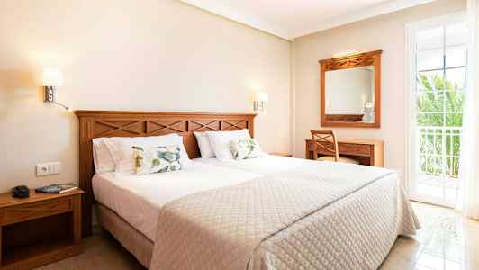 Et hotelværelse med en dobbeltseng, træindretning og en altandør. (AI-genereret tekst)