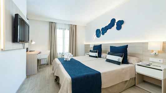 Hotelværelse med to senge og maritimt tema, blåt sengetøj og dekorative puder. (AI-genereret tekst)