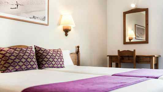 Et hotelværelse med to enkeltsenge dækket med lilla sengetøj, et spejl og et skrivebord. (AI-genereret tekst)