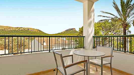 Altan med bord og stole, udsigt til landskab med bakker og grønt. (AI-genereret tekst)