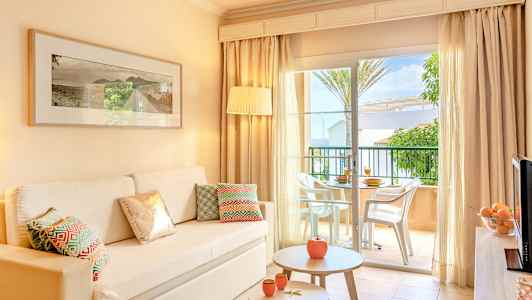 Interiør af lys stue med sofa, bord og åbning mod terrasse. (AI-genereret tekst)