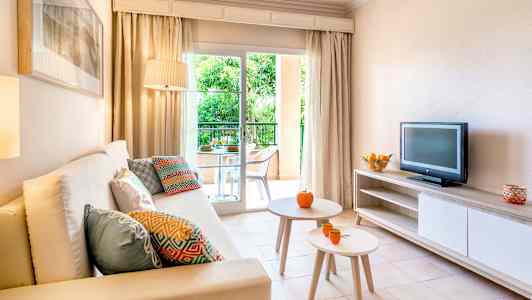 Stue med sofa, bord, tv og adgang til en altan. (AI-genereret tekst)