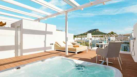 Terrasse med jacuzzi, solseng og udsigt til grønne bjerge. (AI-genereret tekst)