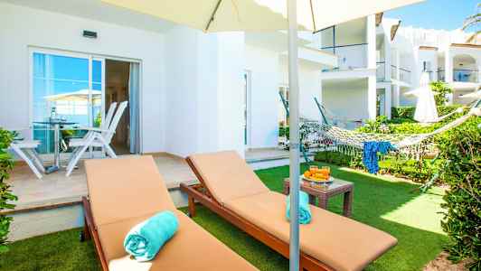 Billede af en haveterrasse med liggestole, en hængekøje og en parasol. (AI-genereret tekst)