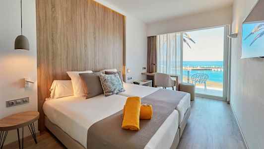 Moderne hotelværelse med udsigt over havet gennem en stor glasdør. (AI-genereret tekst)