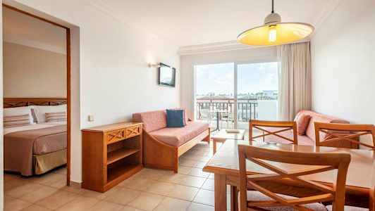 Lejlighedsinteriør med stue og en del af soveværelset synligt. (AI-genereret tekst)