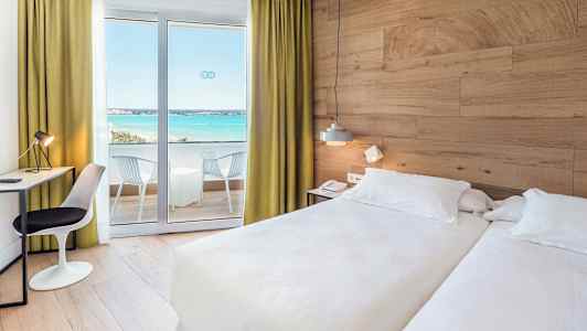 Hotelværelse med to senge, skrivebord og altan med udsigt over havet. (AI-genereret tekst)