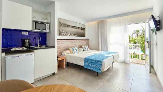 Billede af et hotelværelse med enkeltsenge, tekøkken og en balkon med udsigt. (AI-genereret tekst)