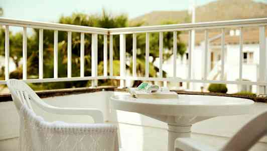 En terrasse med stole og et bord omgivet af rækværk. (AI-genereret tekst)