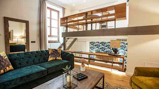 En moderne lejlighed med hems og indrettet med sofa og træbord. (AI-genereret tekst)