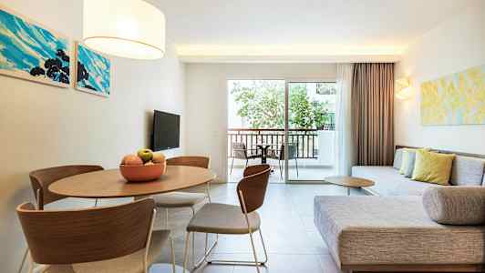 En moderne stue med sofa, bord og stole samt en balkon med udsigt. (AI-genereret tekst)