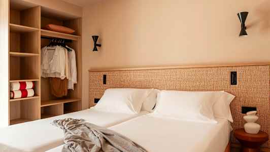 Et hotelværelse med to senge, hvidt sengelinned og et skab til venstre. (AI-genereret tekst)