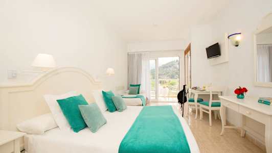 Hotelværelse med hvidt interiør og turkise tekstiler. (AI-genereret tekst)