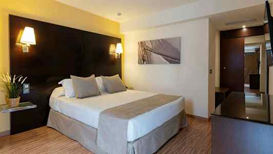 Et hotelværelse med en dobbeltseng, sengelamper og et maleri på væggen. (AI-genereret tekst)