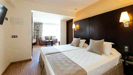 Hotelværelse med to enkeltsenge og et siddeområde. (AI-genereret tekst)