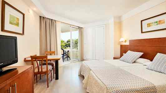 Billede af et hotelværelse med to enkeltsenge, et skrivebord med stole og en altan. (AI-genereret tekst)