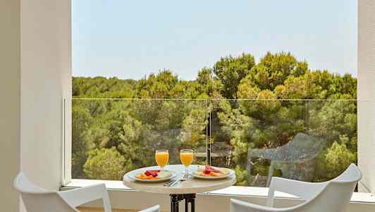 To stole og et bord med morgenmad serveret med udsigt over en skov. (AI-genereret tekst)