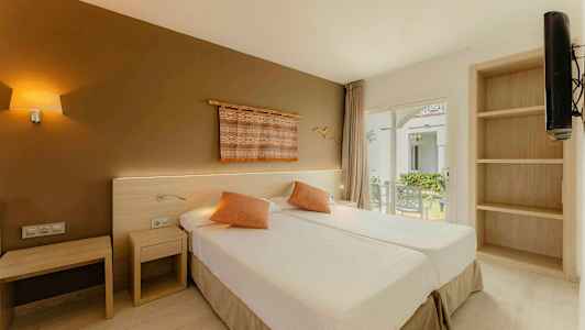 Et hotelværelse med to enkeltsenge, dekorative puder og en væg med kunst. Vindue med udsigt over en have. (AI-genereret tekst)