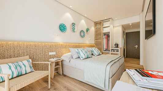 Et hotelværelse med en dobbeltseng, siddeplads og åben garderobeområde. (AI-genereret tekst)