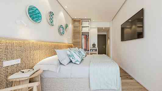 Moderne soveværelse med en dobbeltseng, dekorative tallerkener på væggen og en åben garderobe. (AI-genereret tekst)