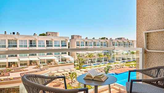 Hotel med poolområde set fra en altan. (AI-genereret tekst)