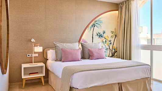 Et moderne soveværelse med en stor seng, dekoreret med pyntepuder og et vægmaleri, der forestiller palmer. (AI-genereret tekst)