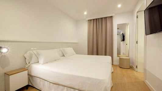 Et hotelværelse med to senge dækket med hvidt sengetøj. (AI-genereret tekst)