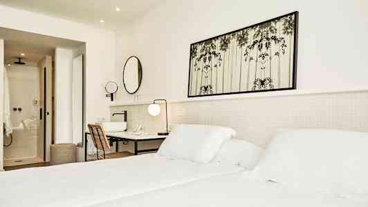 Lyst hotelværelse med seng, skrivebord og badeværelse. (AI-genereret tekst)