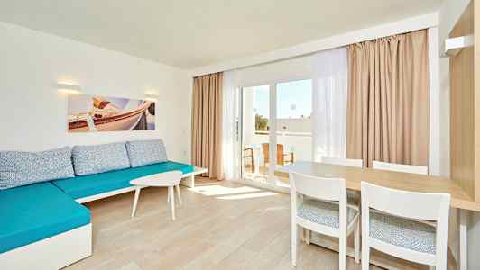 Lyst værelse med blå sofa, et bord med stole og glasdør til altanen. (AI-genereret tekst)