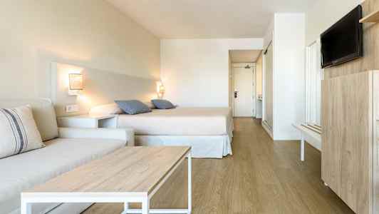 Et hotelværelse med seng, sofa og tv. (AI-genereret tekst)