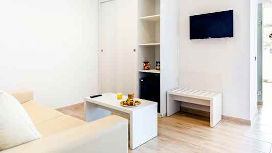 Interiør af en stue med en sofa, sofabord og vægmonteret TV. (AI-genereret tekst)