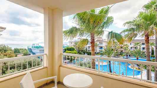 Altan med udsigt over poolområde og palmer. (AI-genereret tekst)