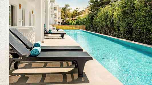 Soldæk med liggestole ved en pool. (AI-genereret tekst)