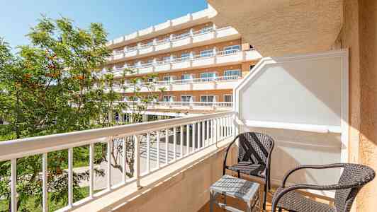 Altan med to kurvestole og et lille bord ved et hotel. (AI-genereret tekst)