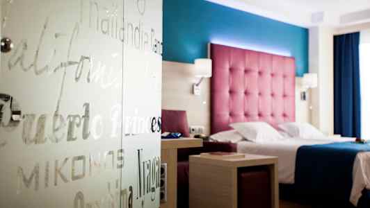 Hotelværelse med farverig indretning, seng og bord. (AI-genereret tekst)