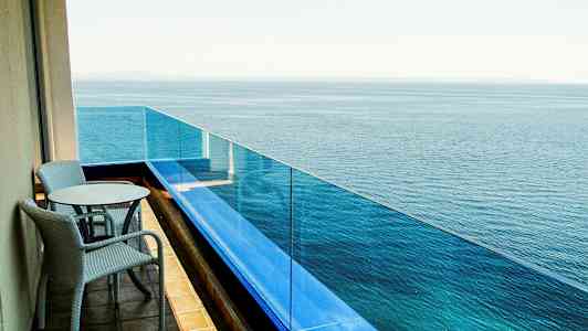 En altan med to stole og et bord vendt mod havet. (AI-genereret tekst)