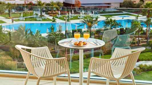 To stole ved et bord med morgenmad i et rum med udsigt over poolområdet. (AI-genereret tekst)