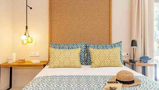 Et værelse med en seng med mønstrede puder og tæppe, samt natbord og dekorative detaljer. (AI-genereret tekst)