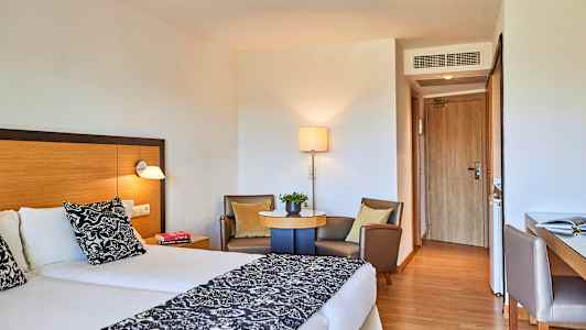 Hotelværelse med to enkeltsenge, siddeområde og skrivebord. (AI-genereret tekst)