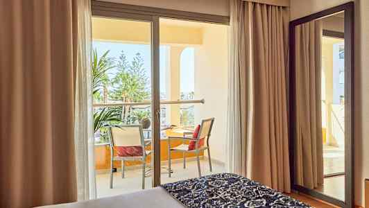 Hotelværelse med altan og udsigt over beplantning. (AI-genereret tekst)